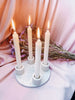 Candle holder with four lit candles on a pink fabric background