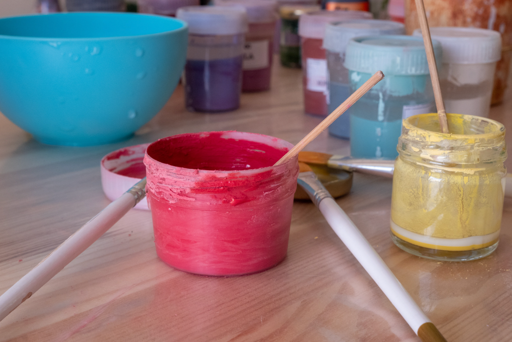 Paint containers with brushes on a wooden surface