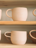 Set of ceramic mugs on wooden shelves